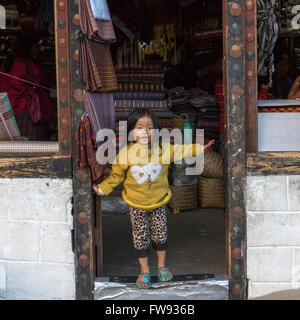 Little girl standing at doorway at store, Paro, Bhutan Stock Photo