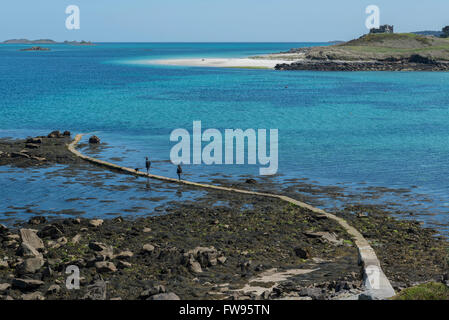 A couple walking on the Old Grimsby harbour slipway at low tide. Tresco. Isles of Scilly. Cornwall. England. UK. Europe Stock Photo