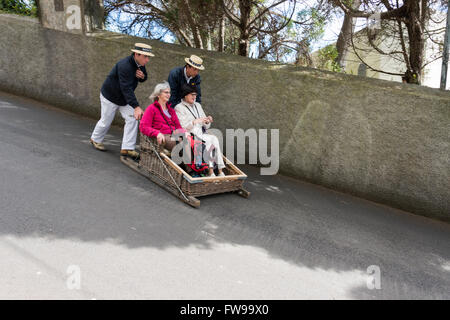 FUNCHAL,PORTUGAL-MARCH 19 Toboggan riders  dive with sledge with tourists on MArch 19, 2016 in Monte- Funchal, Portugal. This is Stock Photo