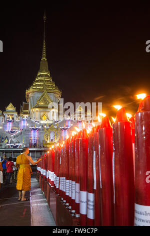 Illuminated Phra Maha Mondop of the Wat Traimit temple, monk lighting candles at the Chinese New Year, Chinatown, Bangkok Stock Photo