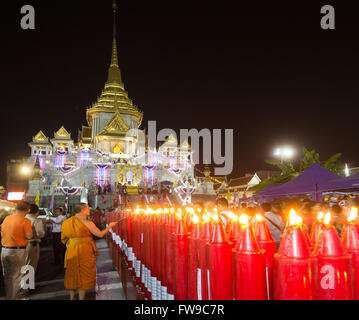 Illuminated Phra Maha Mondop of the Wat Traimit temple, monk lighting candles at the Chinese New Year, Chinatown, Bangkok Stock Photo