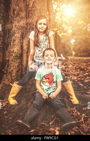 two children sitting by tree Stock Photo