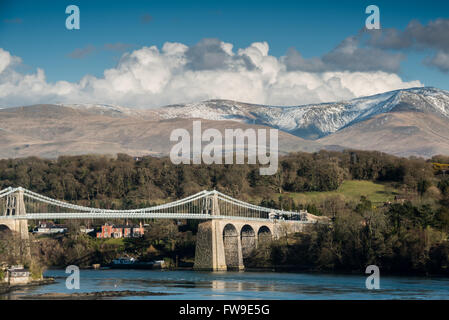 The Menai bridge crossing from Anglesey to the mainland, with the snow spattered Carneddau mountains in the distance. Stock Photo