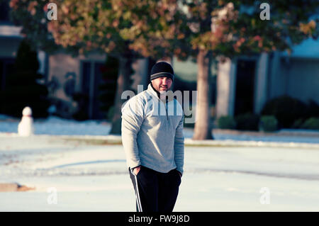 Man in toboggan standing in snow looking at camera in a residential neighborhood. Stock Photo