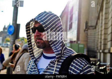 Middle age man with backpack wearing a hood traveling the city. Stock Photo