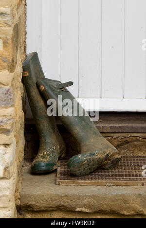 wooden front door with wellington boots in doorway at a countryside cottage Stock Photo