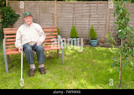 Portrait of an elderly man sitting in his garden smiling Stock Photo