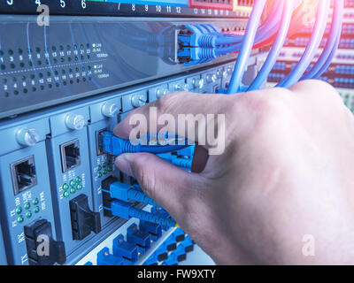 hand of administrator holding optic fiber cables with connectors Stock Photo