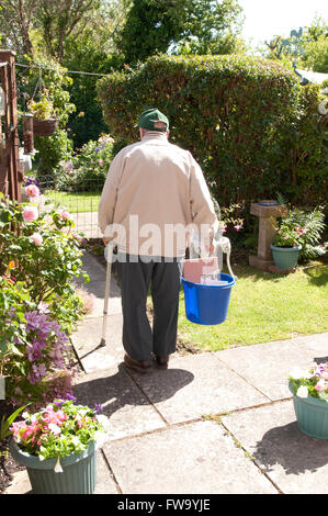 Rear view of an elderly man with a walking stick taking out his recycling Stock Photo