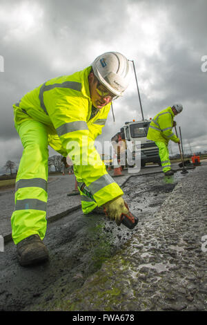 Road workers marking out faults on tarmac Stock Photo