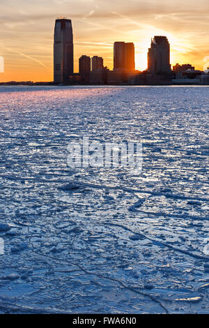 Winter view of the Frozen Hudson River and ice at sunset with skyline of Jersey City skyscrapers (near Paulus Hook Pier)