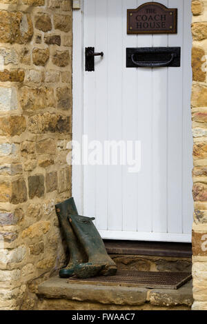 wooden front door with wellington boots in doorway at a countryside cottage Stock Photo