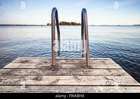 Wooden pier for swimming on still lake coast Stock Photo