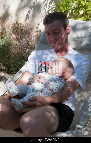 Father and baby lying together on a sun lounger Stock Photo
