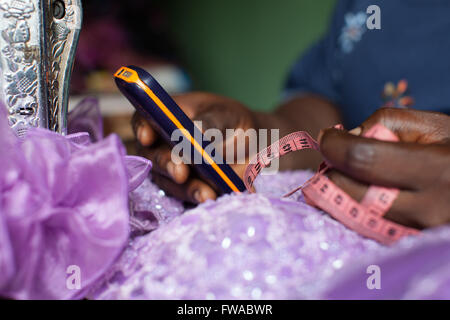 A female dress maker using her mobile for business, Nigeria, Africa Stock Photo