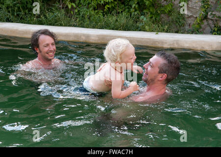Family on holiday playing around in a swimming pool Stock Photo