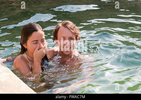 Young couple on holiday playing around in a swimming pool Stock Photo