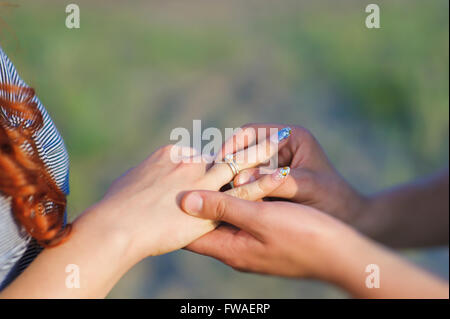Man making proposal with the ring to his girlfriend. Put ring on hand. Stock Photo