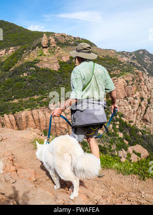 Hiker and dog on the MIshe Mokwa Trail at Circle X Ranch, with Echo Cliffs, rock climbers and Balanced Rock in background Stock Photo