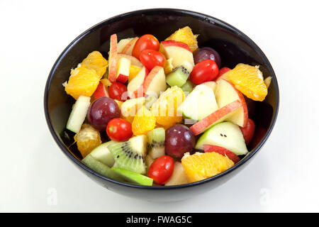 Mixed fruit salad put salad dressing. Colorful fruit salad in black dish.On white background. Stock Photo