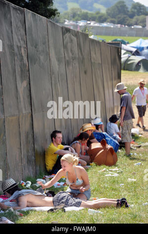 Revelers use any available shade at the Glastonbury Festival 2010, Pilton Somerset UK Stock Photo