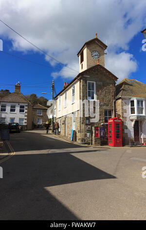 Red phone box in front of the harbour authority office and clock tower at Mousehole, Cornwall, UK Stock Photo