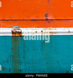 rusty metal bow of old fisher boat hull in orange blue and white Stock Photo
