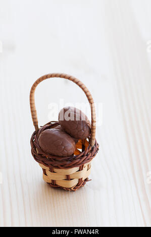 Chocolate easter eggs in a basket on a wooden table Stock Photo