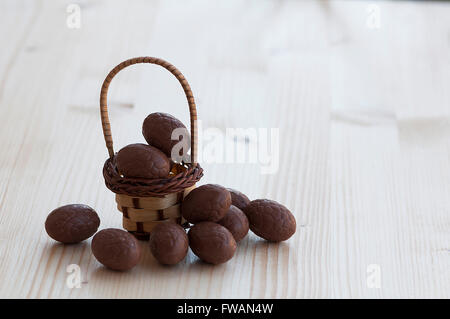 Chocolate easter eggs in a basket on a wooden table Stock Photo