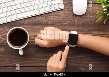 hand using smartwatch on desk top view Stock Photo