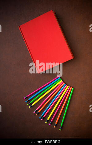 Wooden writer desktop with colorful pencil and red empty cover book, vertical frame Stock Photo