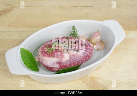 raw ham with rosemary and laurel in dish Stock Photo