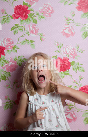 Girl with a patterned wall paper pulling face Stock Photo