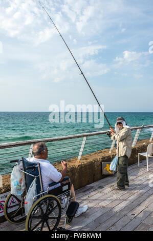 Man fishing on a promenade in Tel Aviv Port district in Tel Aviv city, Israel Stock Photo