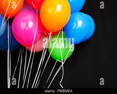 Group of colorful balloons on ribbons over black background Stock Photo