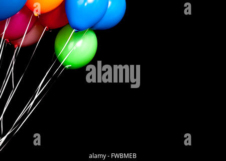 Colorful balloons on ribbons over black background Stock Photo