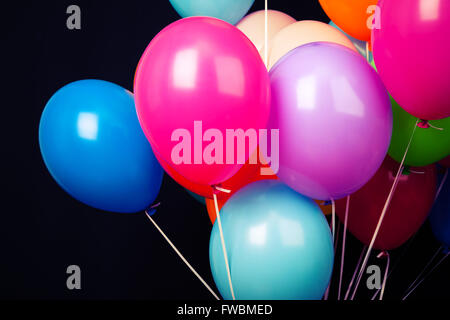 Group of colorful balloons on ribbons on black background Stock Photo