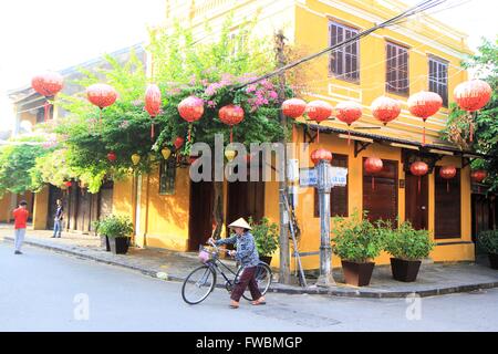 Woman pushing a bike in the streets of old town Hoin An, Vietnam, Asia Stock Photo