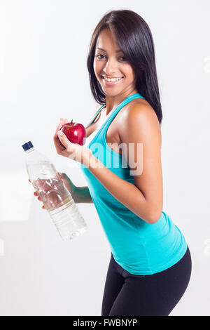 Fitness woman happy smiling holding apple and water bottle. Stock Photo