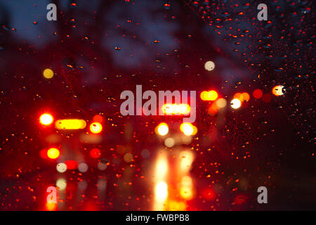 Flashing red and yellow lights of emergency vehicles and firetrucks seen on a rainy night through a wet car windshield Stock Photo