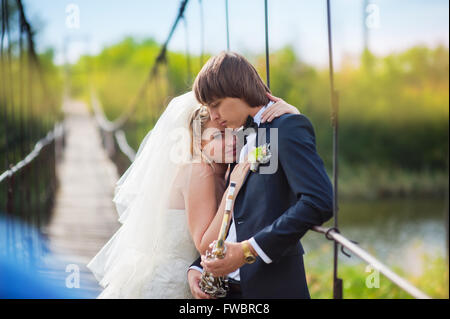 Young happy bride and groom standing on a bridge Stock Photo