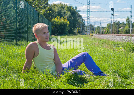 Young man in yellow sitting on the green grass Stock Photo