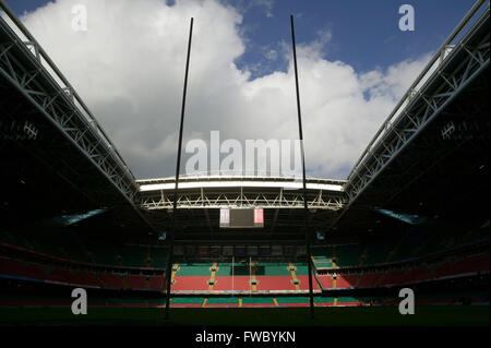Rows of plastic seating in red and green circle the pitch which is set with rugby posts at the Millenium Stadium in Cardiff, Wales. Stock Photo