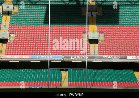 Rows of plastic seating in red and green circle a stadium' pitch which is set with rugby posts. Stock Photo