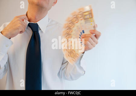Man fanning himself with bank notes. Stock Photo