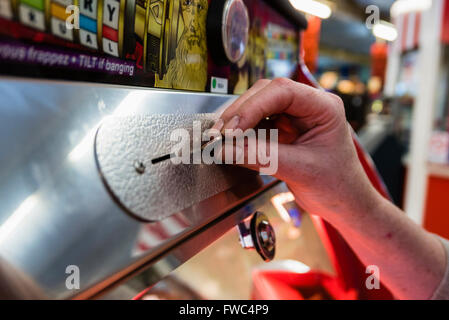 A woman plays a 2p tuppeny nudger machine in a funfair at a British seaside resort. Stock Photo