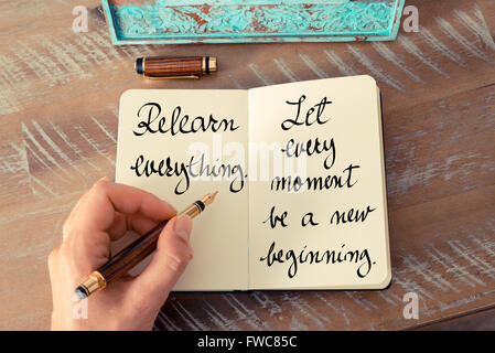 Retro effect and toned image of a woman hand writing on a notebook. Handwritten quote Relearn everything. Let every moment be a new beginning as inspirational concept image Stock Photo