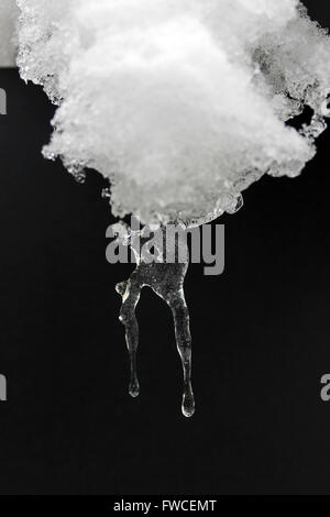 Icicle formed from melting snow covering a patio table Stock Photo