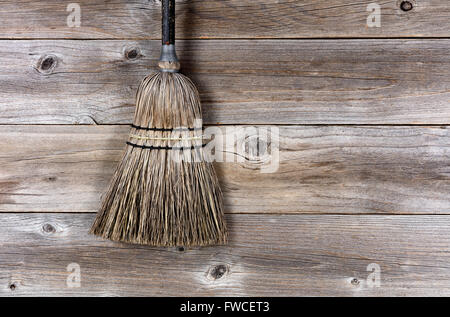 Old straw broom on stressed wooden floor. Stock Photo