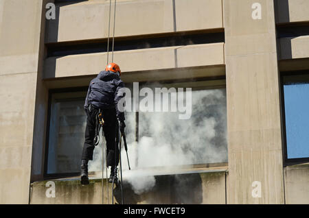 Rope access, abseiling, window cleaning access for hard to reach glass and stonework. Male working at height using ropes. Person. 10 Spring Gardens Stock Photo